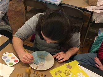 A student painting a plate