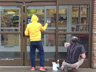 2 students washing the glass door of a store
