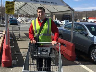 A student wearing a reflective vest pushing a shopping cart